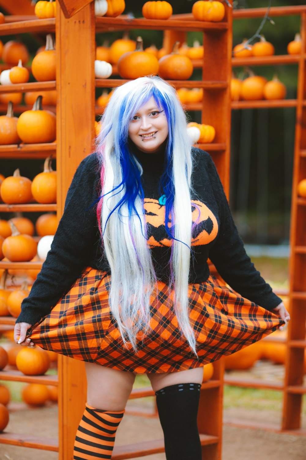 a woman with long white hair and blue hair posing in front of pumpkins
