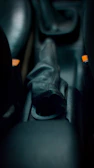 Close-up of a sleek gear shifter with red accents under bright industrial lighting.