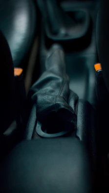 Close-up of a sleek gear shifter with red accents under bright industrial lighting.