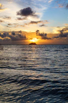 Sunrise over the ocean with a cruise ship silhouette on the horizon.