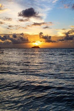 A serene cruise ship cabin balcony overlooking calm ocean waters at sunset.