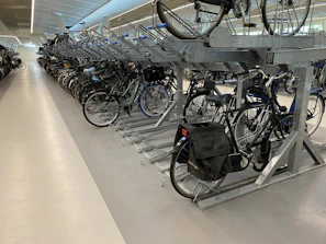 Bicycles secured in a covered parking area featuring racks and safety signage.
