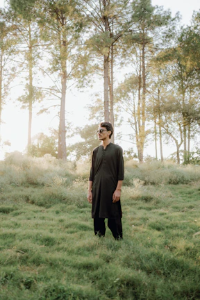 A model wearing a cozy, earth-toned traditional outfit standing in a sunlit field.