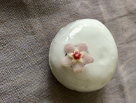 A delicate ceramic piece with smooth curves and a matte finish displayed on a wooden pedestal.