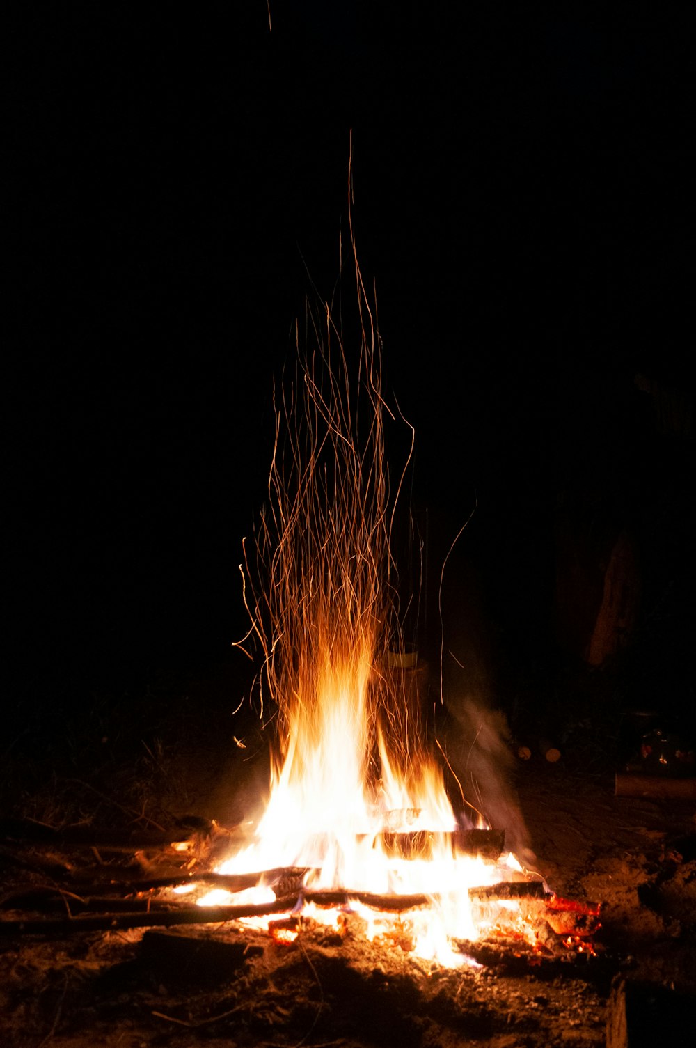 a campfire is lit in the dark with long sticks sticking out of it