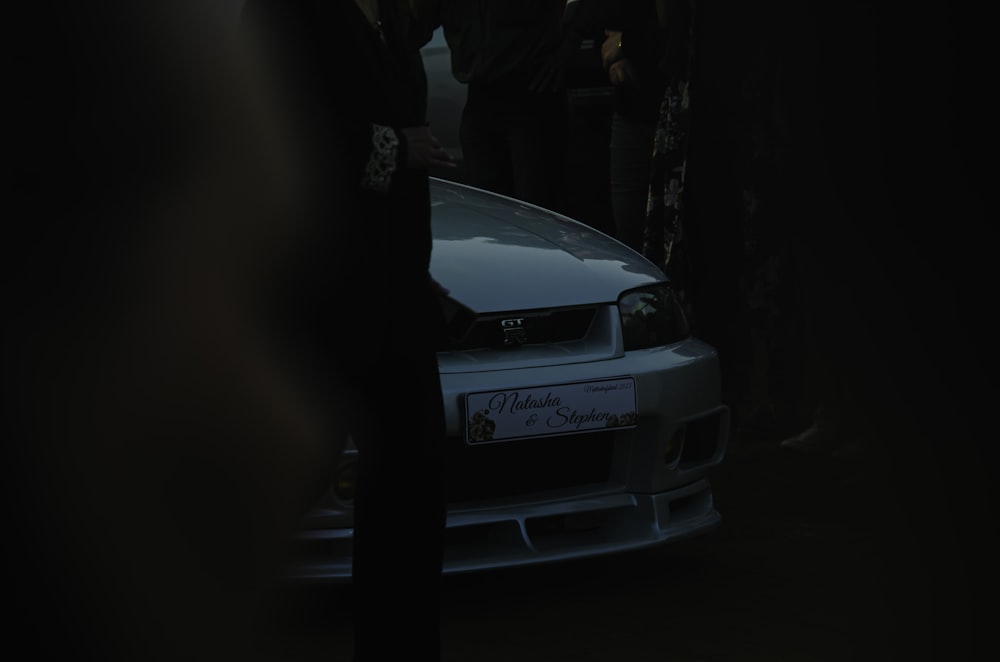 a group of people standing around a white car