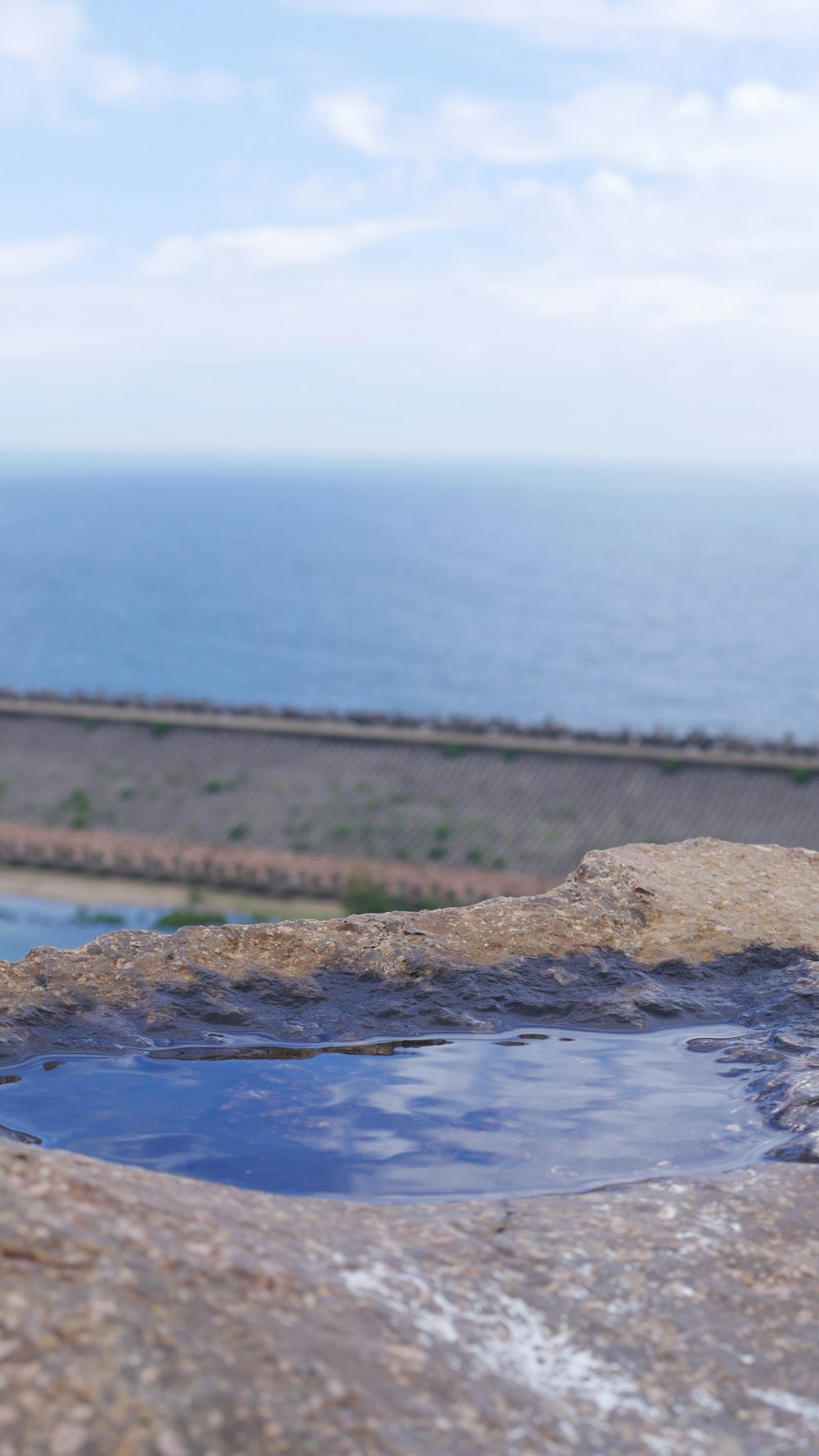 a hot tub sitting on top of a rock next to the ocean