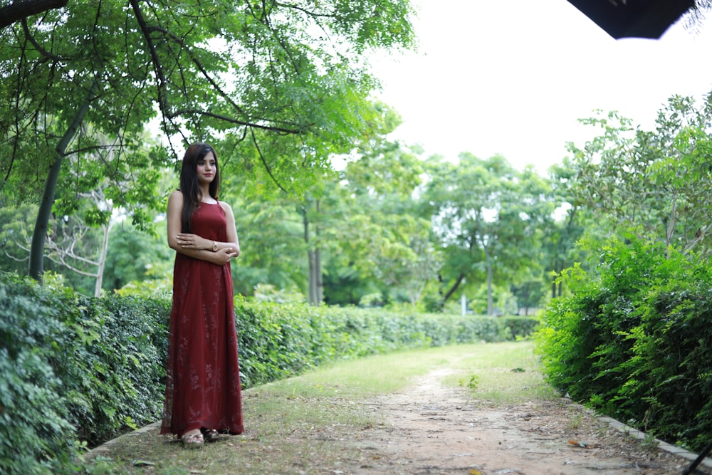 a woman in a long red dress standing on a path