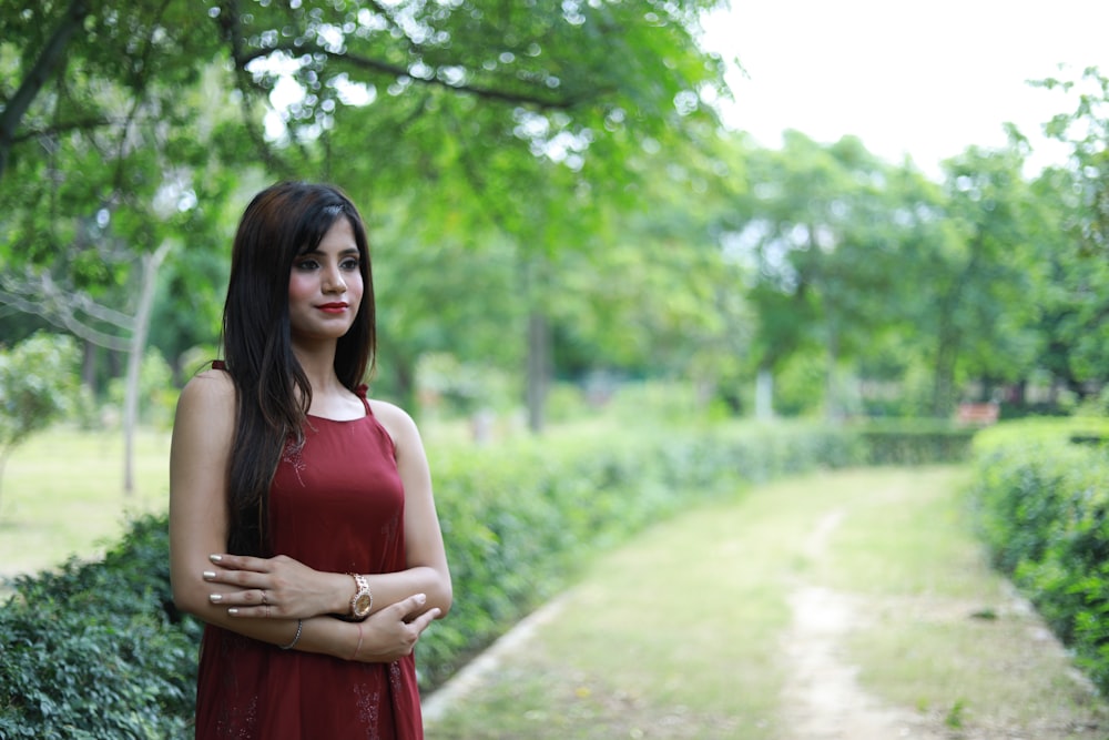 a woman in a red dress standing in a park