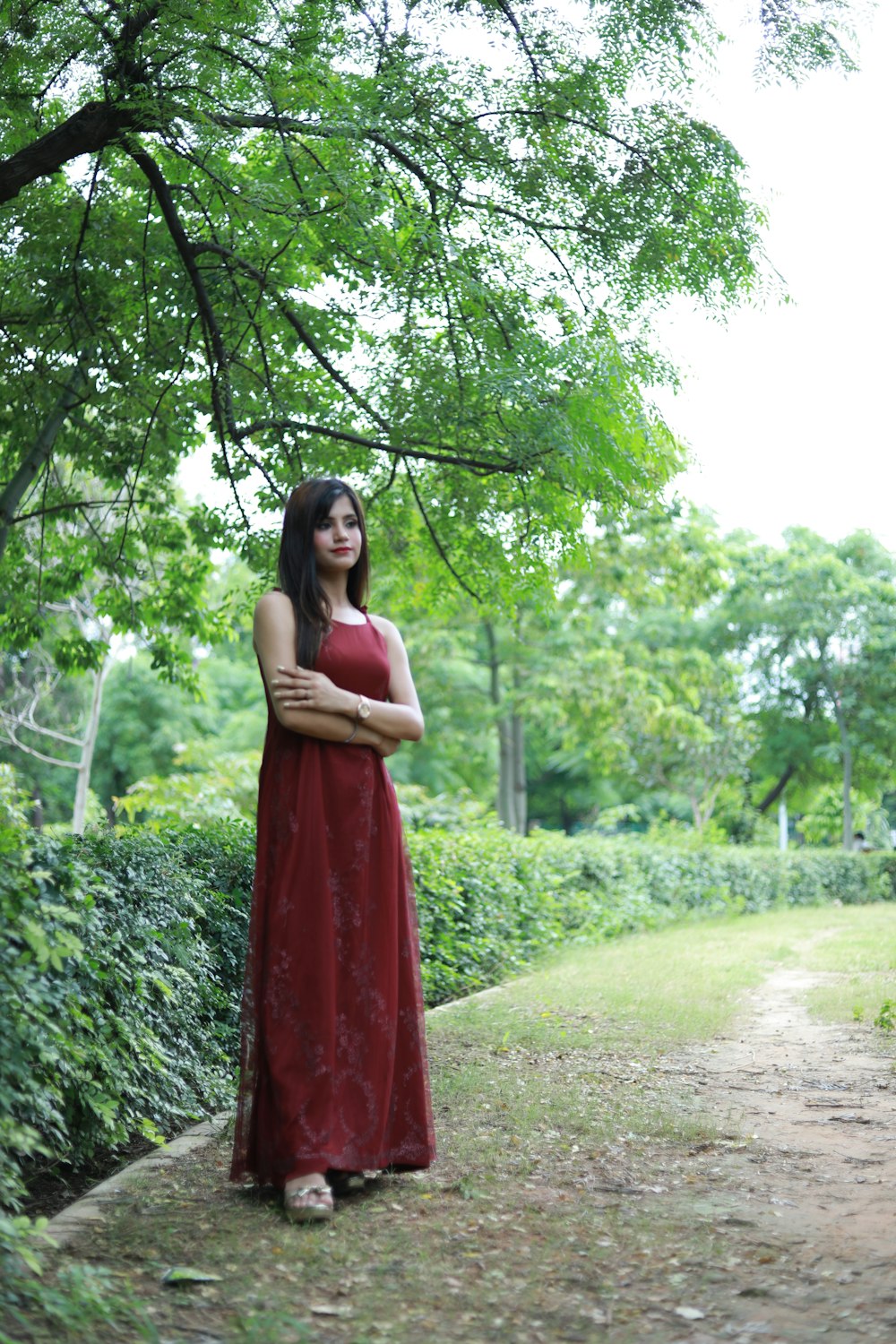 a woman in a red dress standing under a tree