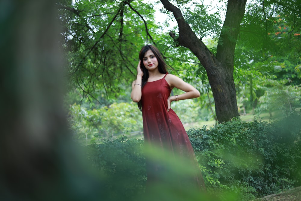 a woman in a red dress standing in the woods