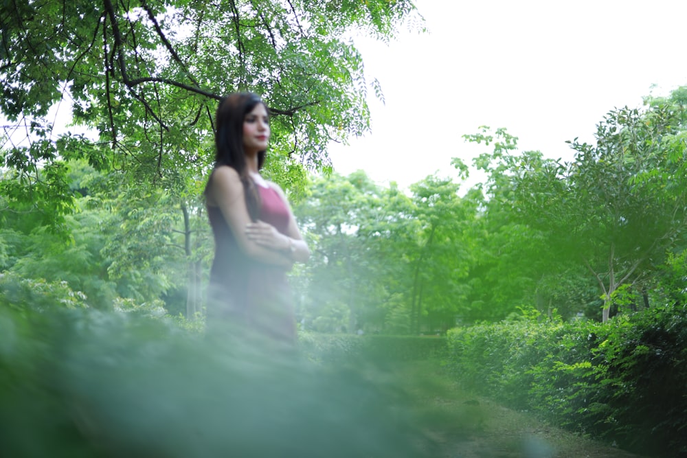 a woman standing in the middle of a forest