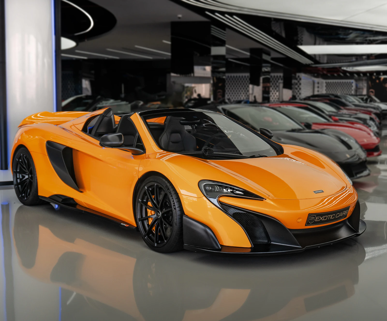 Orange McLaren 675LT Spider in a showroom with other supercars behind it