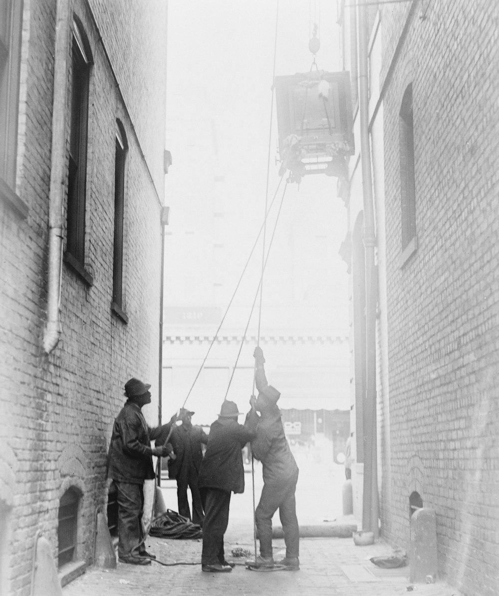 Three African American men lifting a piece of equipment, with block and tackle, at the Standard Engraving Company, Washington, D.C.