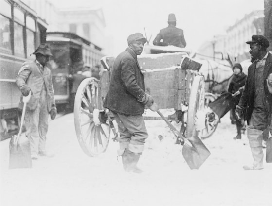 A snow removal team clearing a busy street in Vilnius on a bright winter day.