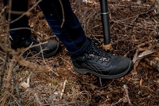 Close-up of lightweight trekking poles planted firmly in forest soil covered with autumn leaves
