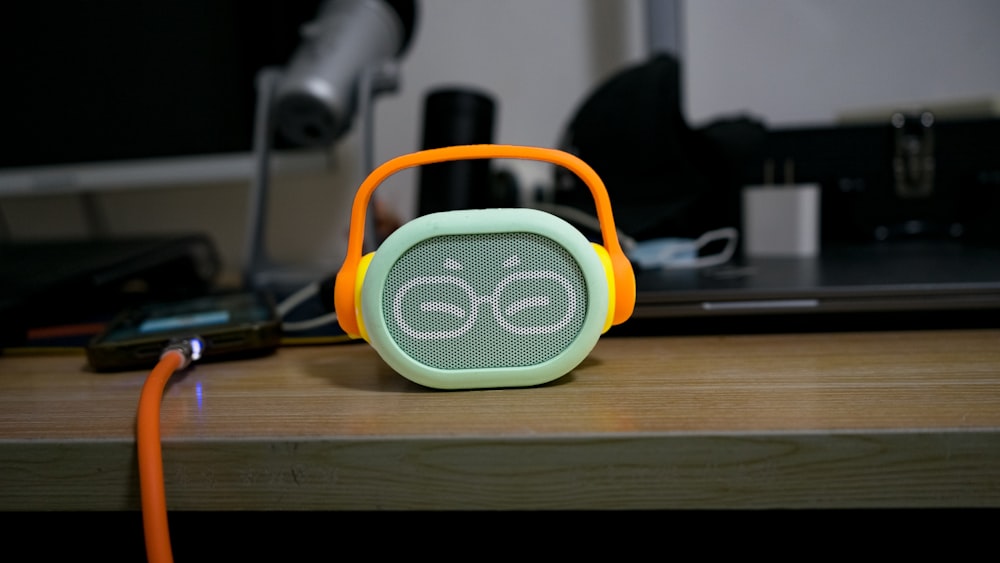 a green and orange speaker sitting on top of a wooden table