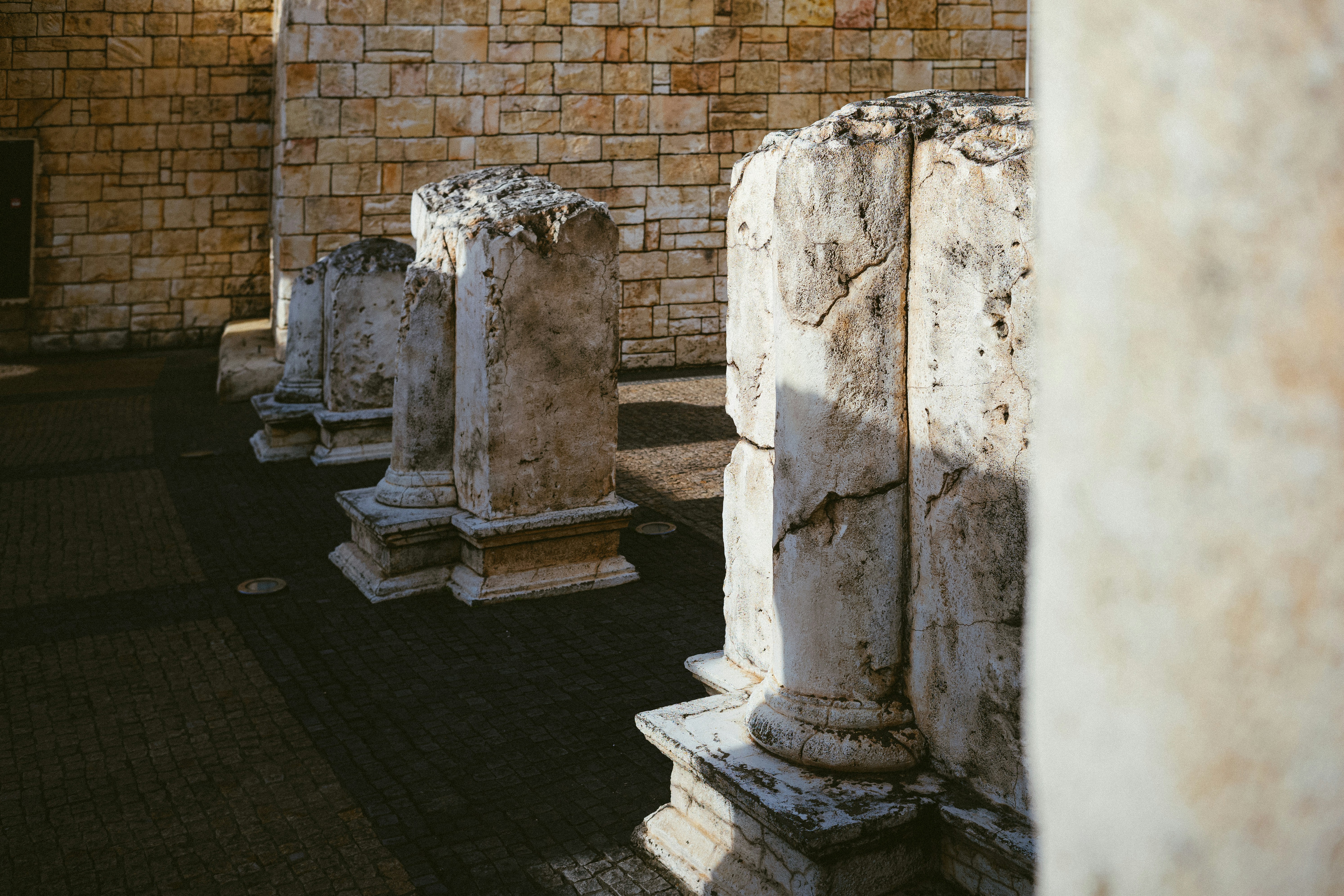 a row of stone pillars in front of a brick wall