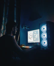 Engineer adjusting 3D model on computer screen under soft grey lighting.