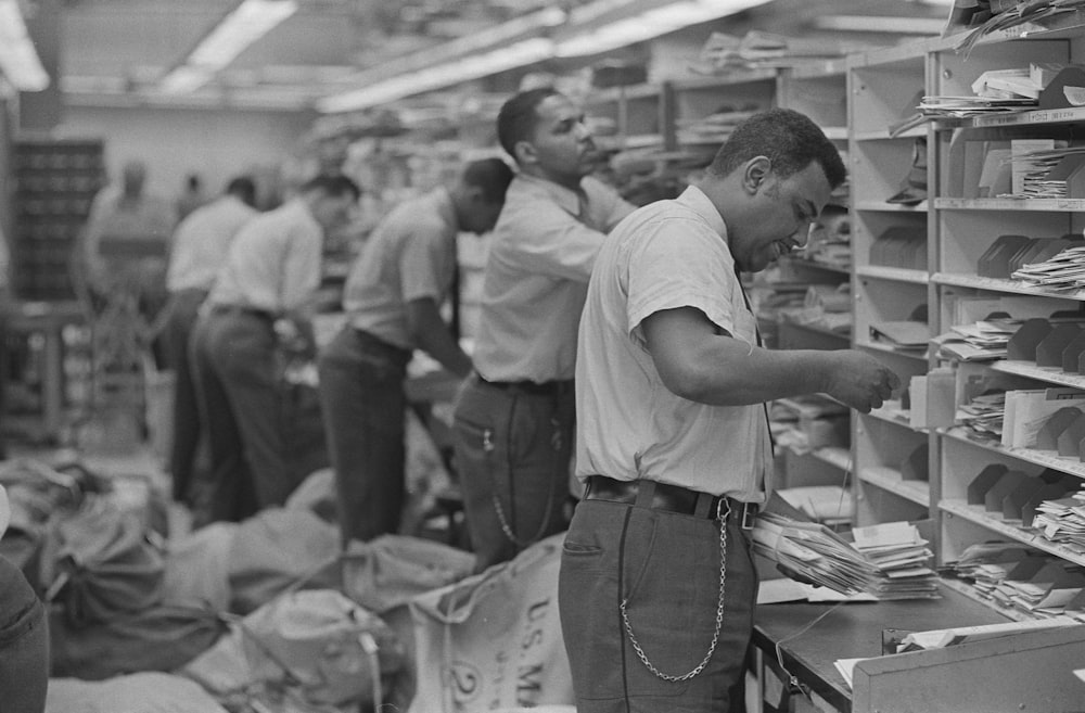 African American postal employees sorting mail into cubby-holes.