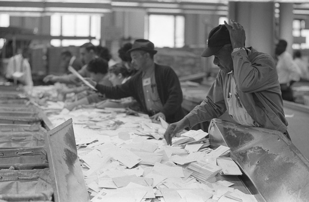 African American postal employees sorting mail on table.