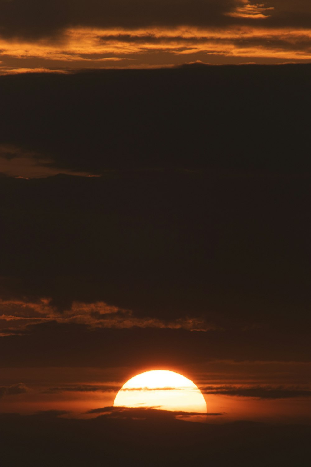 the sun is setting over the horizon of a cloudy sky