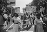 A procession of African Americans carrying signs for equal rights, integrated schools, decent housing, and an end to bias. 