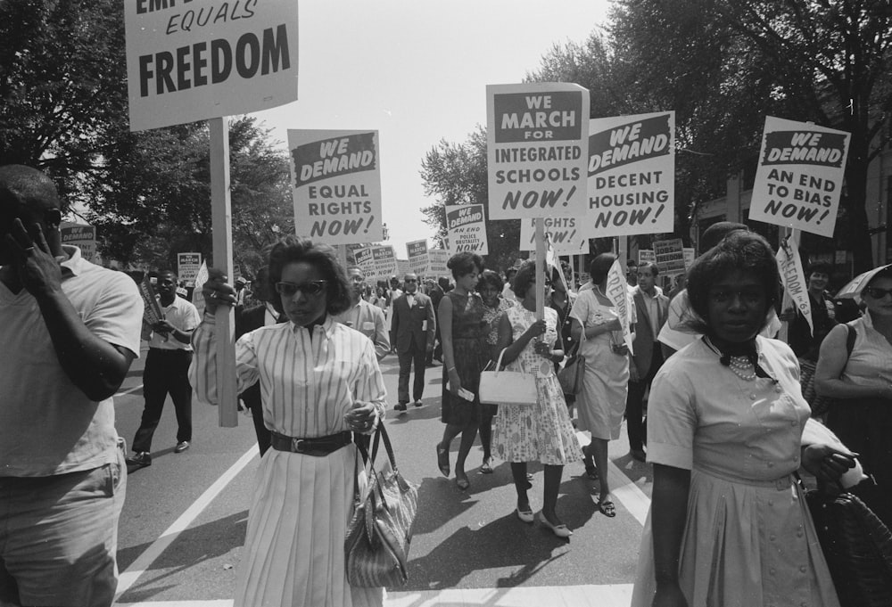 A procession of African Americans carrying signs for equal rights, integrated schools, decent housing, and an end to bias. 