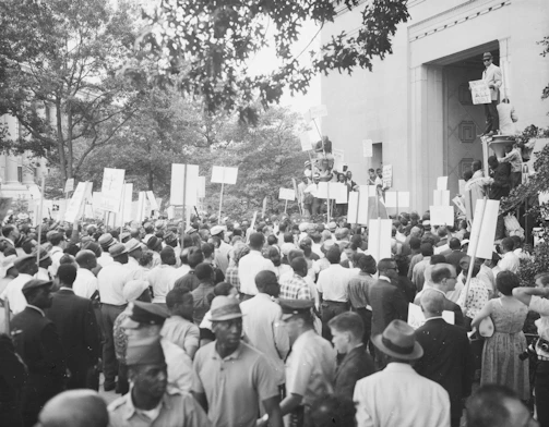 Crowd gathered outside a government building holding placards during a protest.