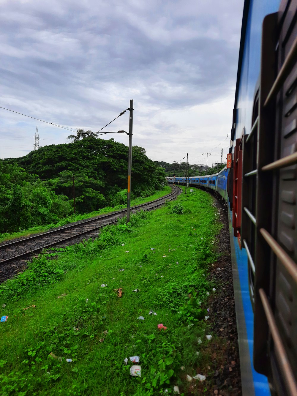 a train traveling down train tracks next to a lush green hillside