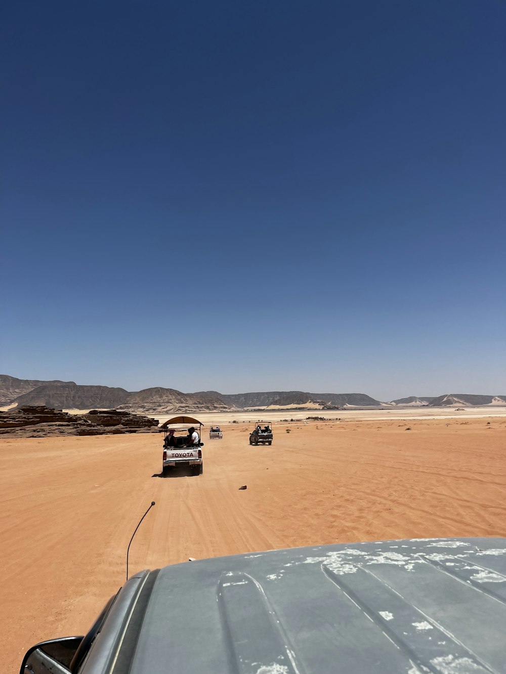 a group of vehicles driving through the desert