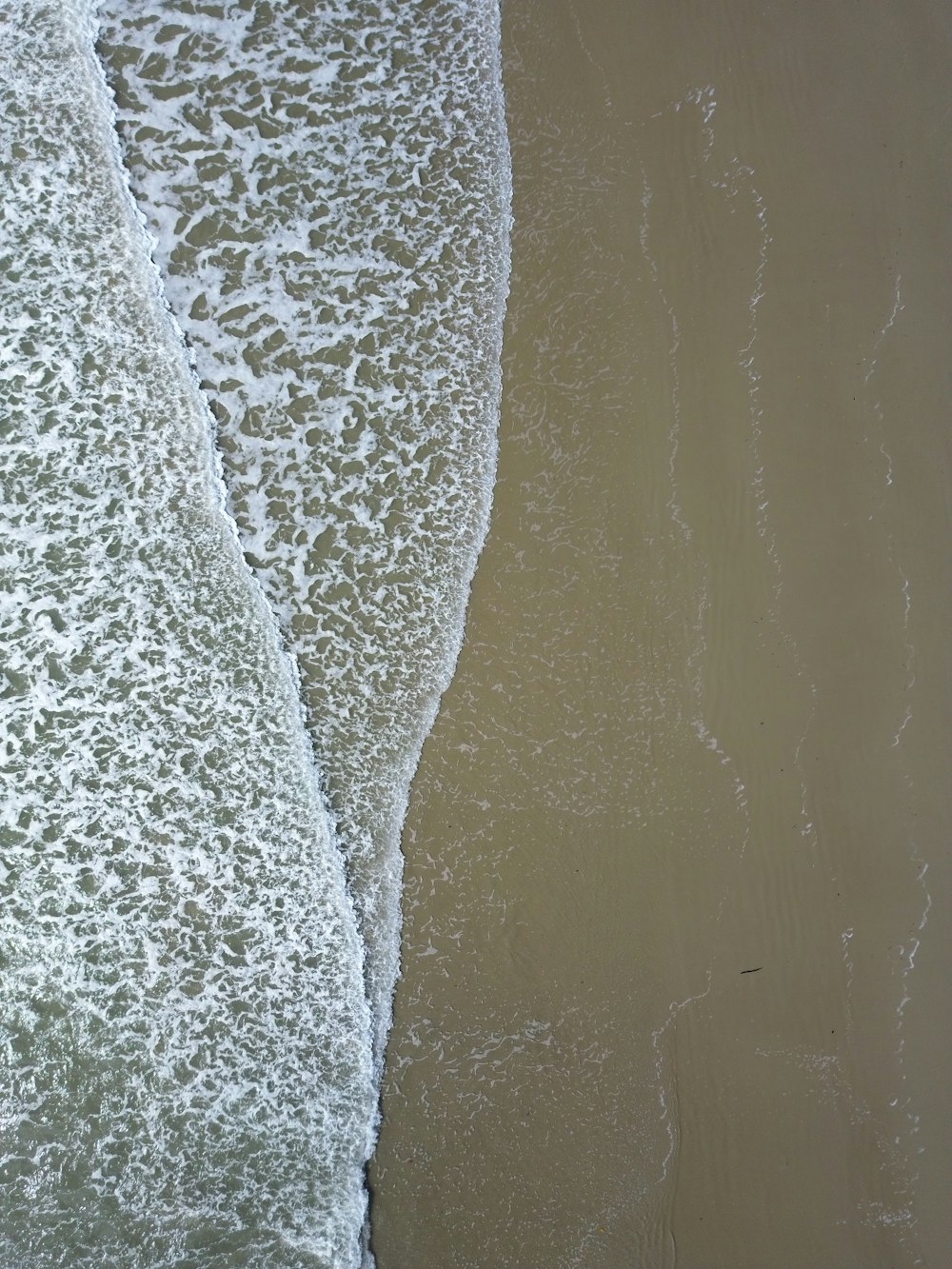 an aerial view of a beach with a surfboard in the water