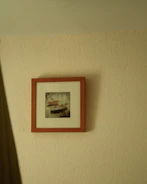 Framed minimalist landscape print with soft pastel colors hanging on a white wall.