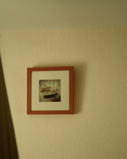 Close-up of a muted beige and warm taupe abstract painting hanging on a textured plaster wall.