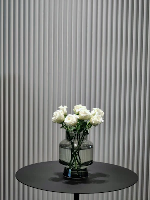 Elegant single-stem roses arranged in a minimalist glass vase on a wooden table.