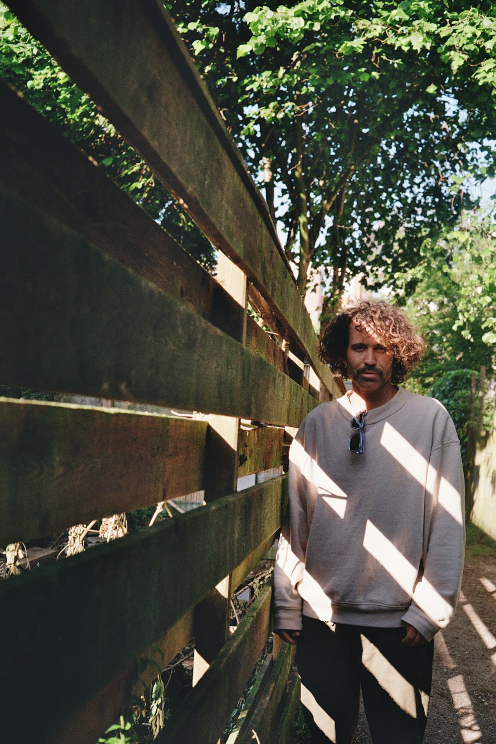 a man standing next to a wooden fence