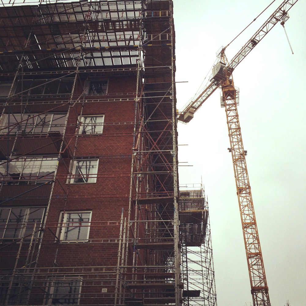 a crane is standing next to a tall building