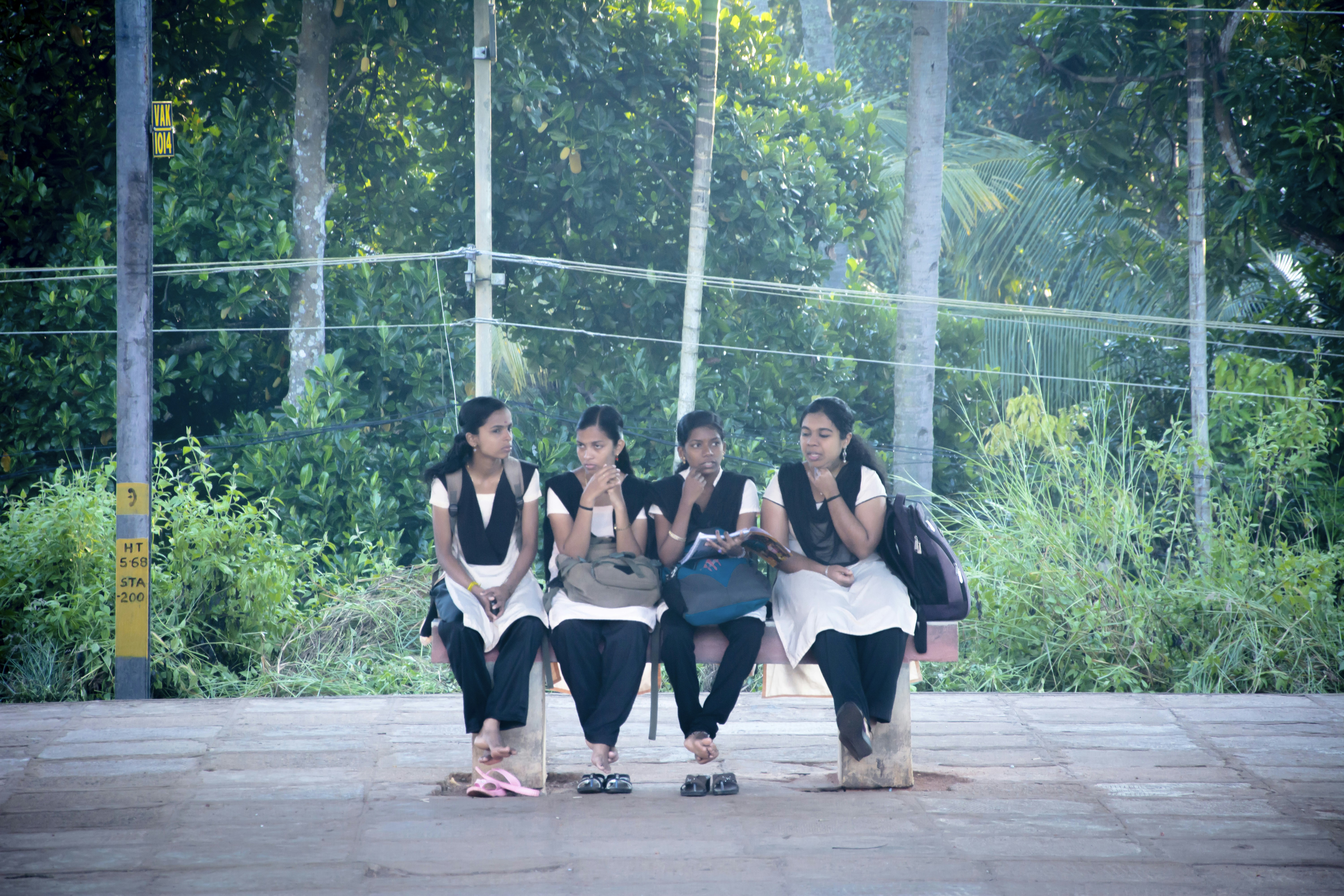 a group of girls sitting on a bench in the rain