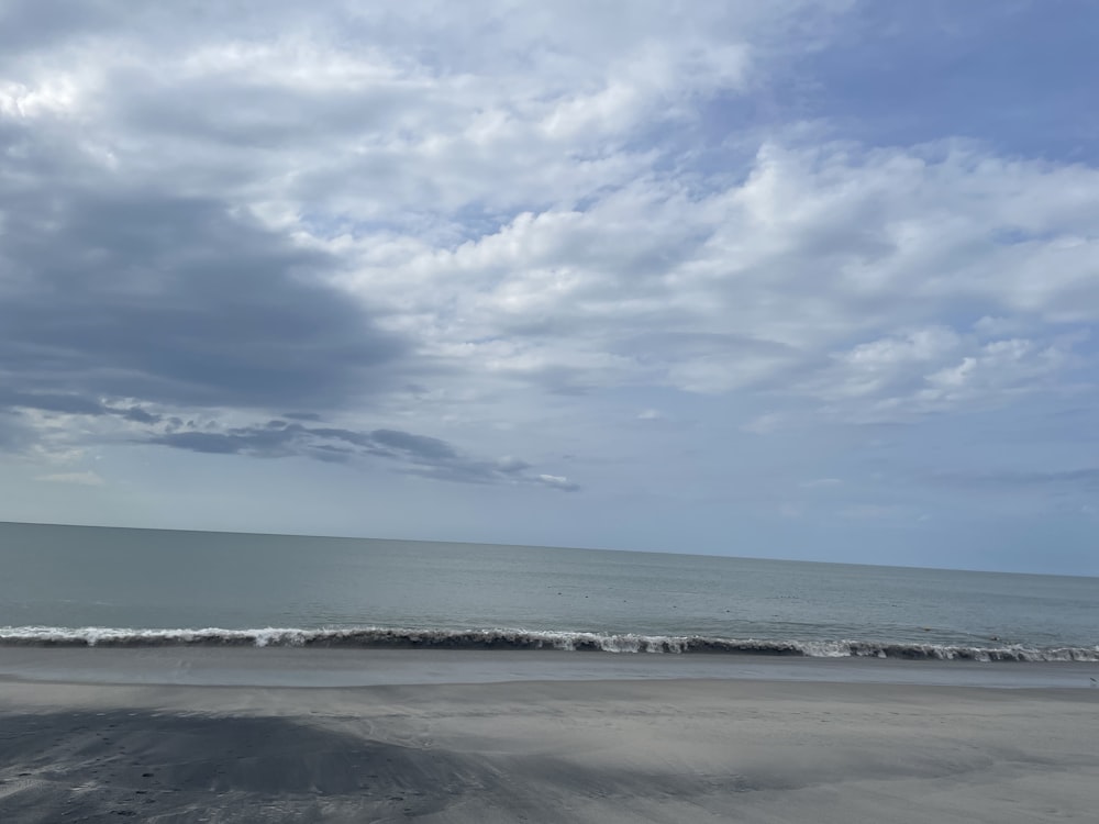 uma praia de areia com ondas entrando na costa