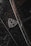 A close-up of a luxury car emblem adorned with raindrops, showcasing sleek chrome details against a dark, glossy surface.