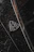 A close-up of a luxury car emblem adorned with raindrops, showcasing sleek chrome details against a dark, glossy surface.