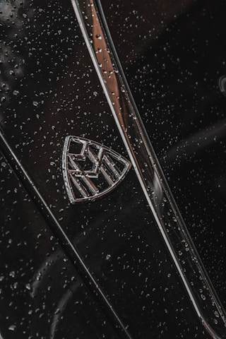 Close-up of a polished luxury car emblem gleaming under showroom lights.