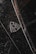 A close-up of a luxury car emblem adorned with raindrops, showcasing sleek chrome details against a dark, glossy surface.