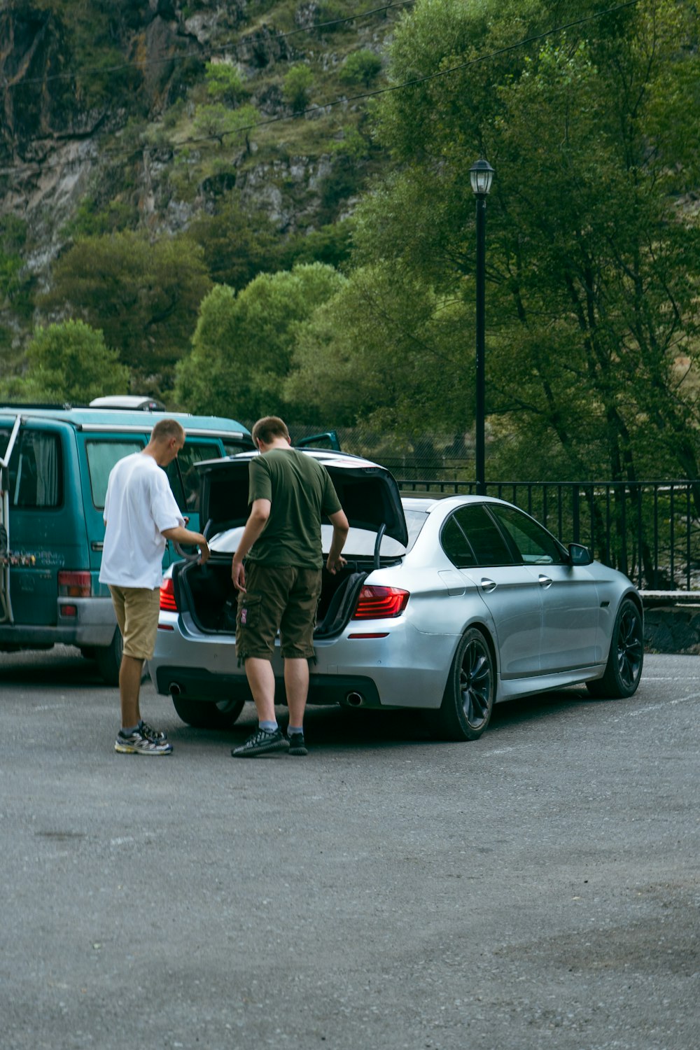 a couple of men standing next to a silver car