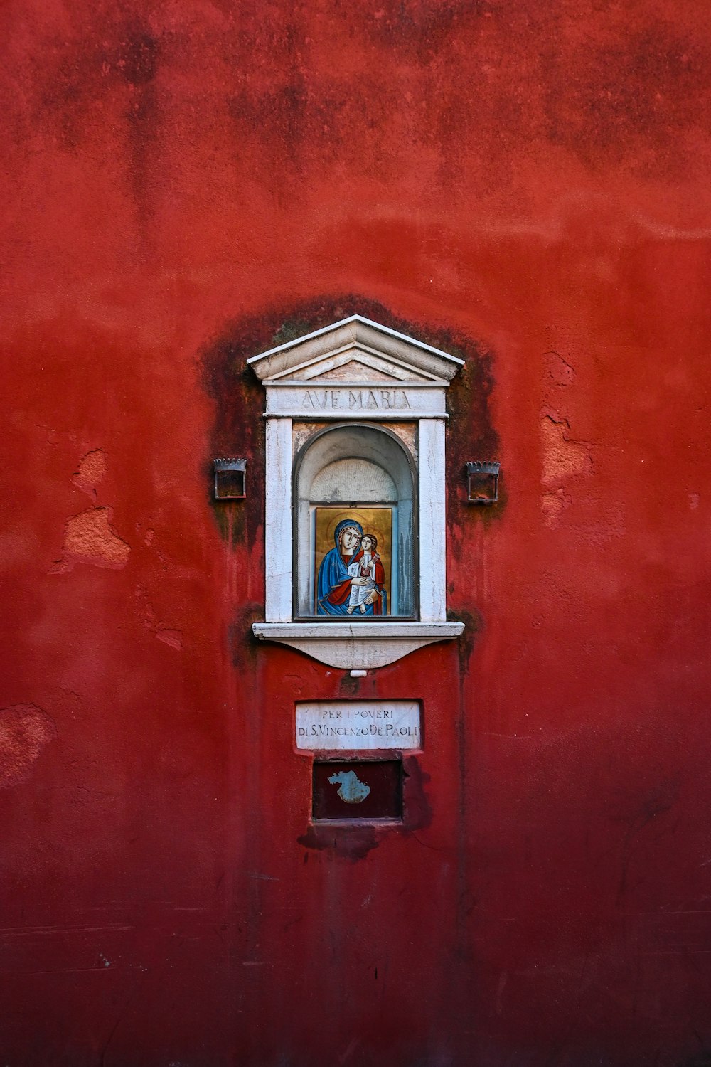 a red wall with a window and a painting on it