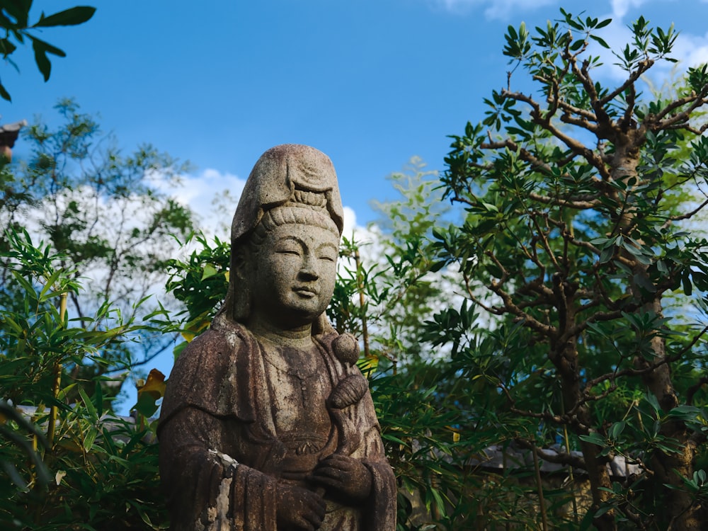 a statue of a buddha sitting in the middle of a forest