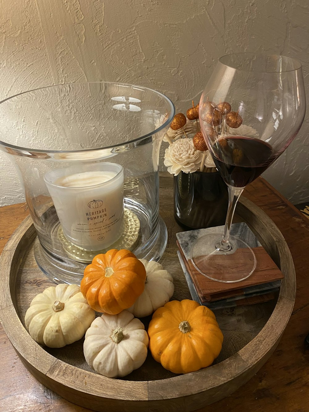 a glass of wine and some pumpkins on a tray