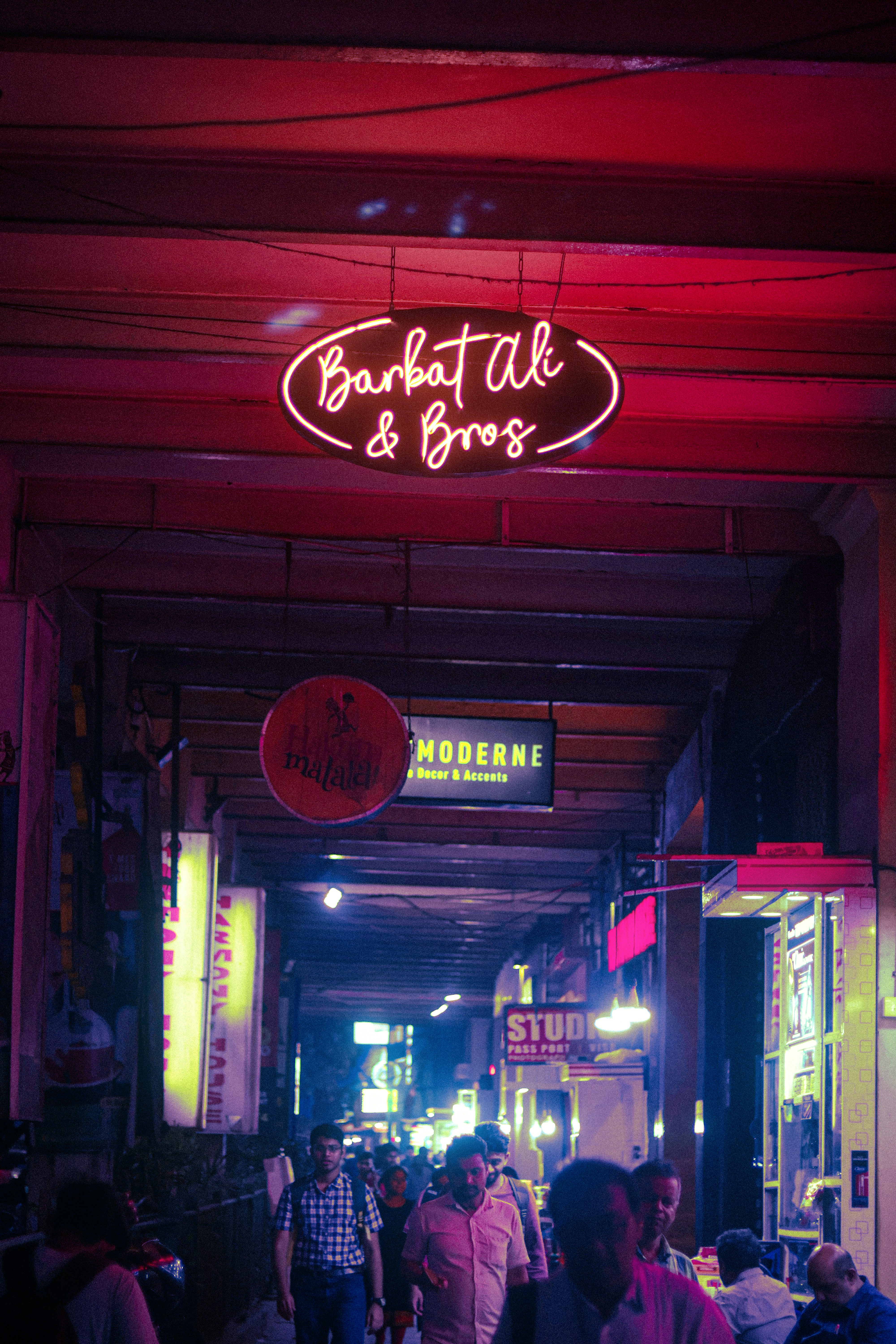 a group of people standing under a neon sign