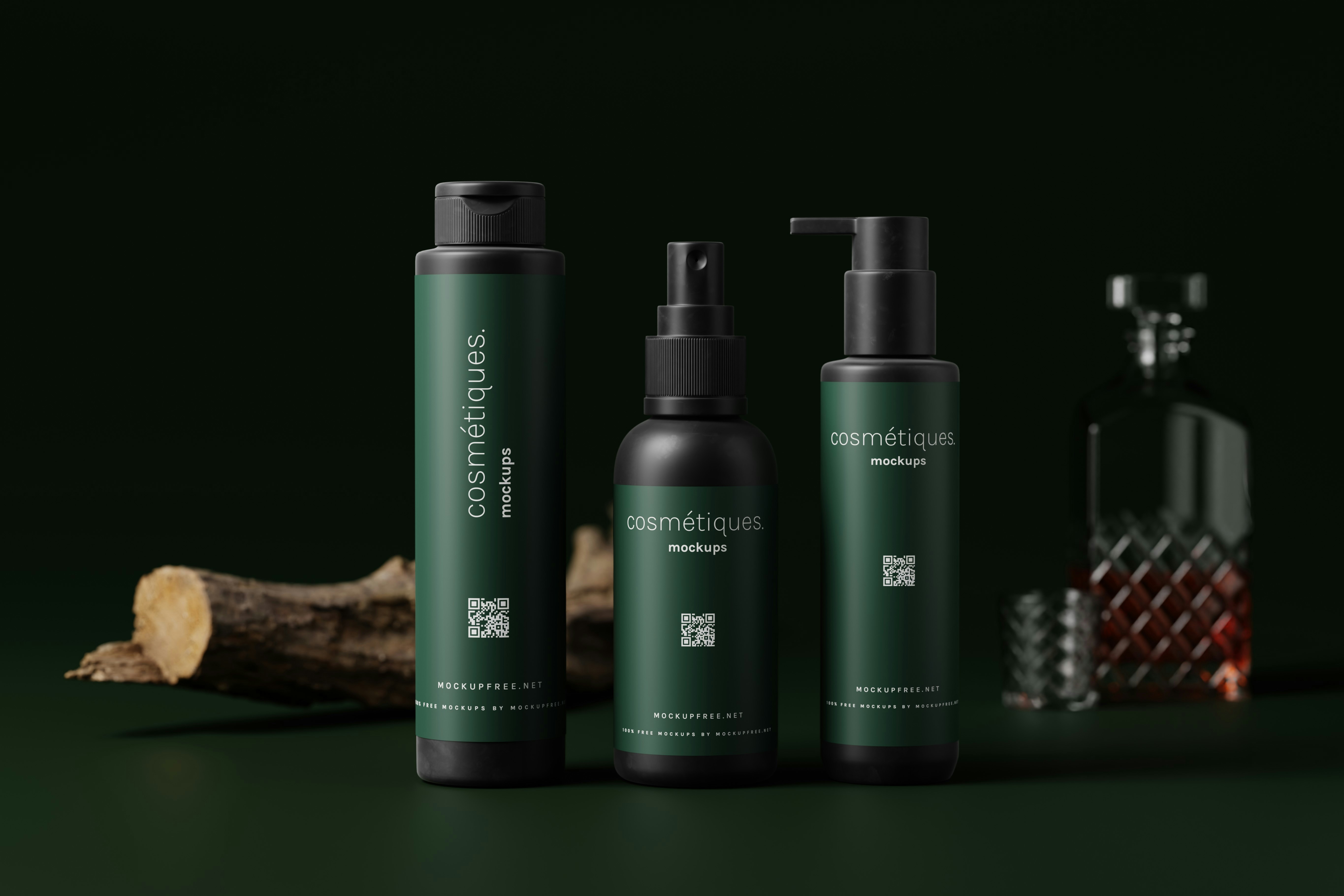 Three dark green cosmetic bottles with black caps are arranged in the foreground. Each bottle has the word 'cosmétiques' written on it. In the background, there is a glass decanter with a patterned design, partially filled with a brown liquid. A piece of wood is lying on the left side, adding a natural element.