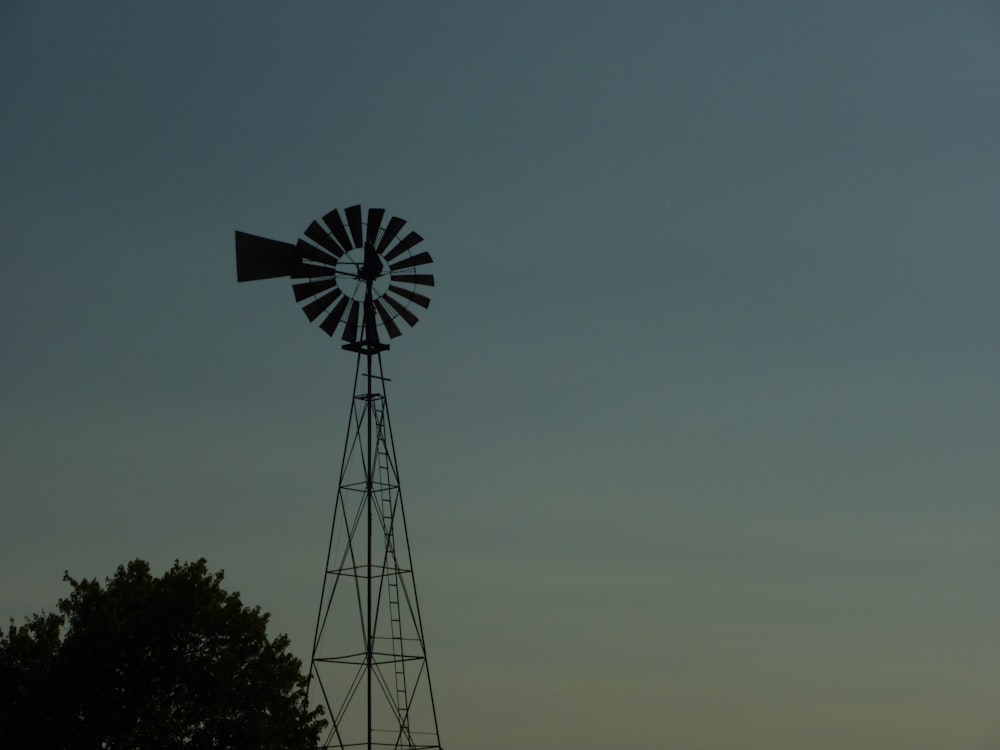 a windmill on top of a hill with trees in the foreground